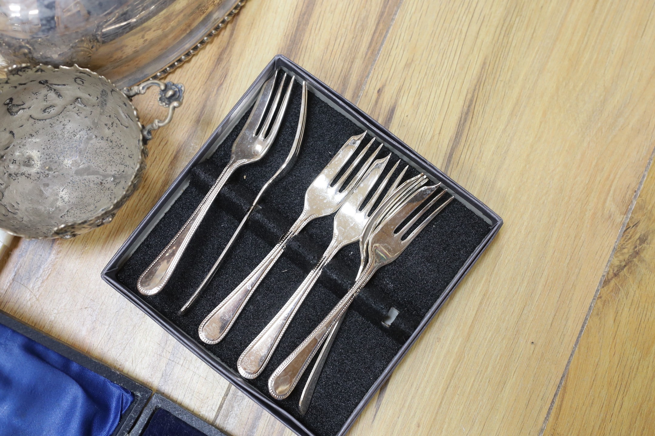 A cast white metal bowl and a collectio of plated items including a hot water pot, meat cover, cased flatware, etc.
